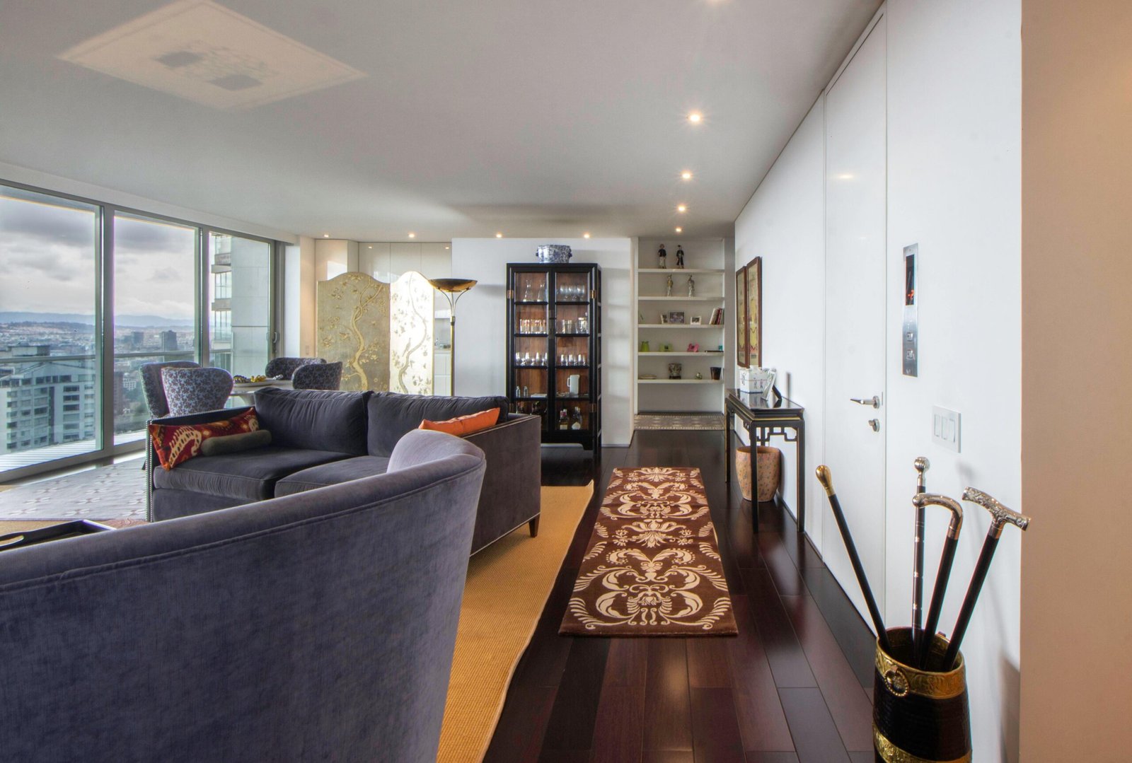 Spacious living room interior with cityscape view, modern furnishings, and decorative elements.